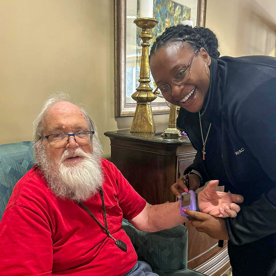 Senior resident receives a friendly wellness check from a smiling staff member in a comfortable living space, highlighting care and attention at a senior living community.